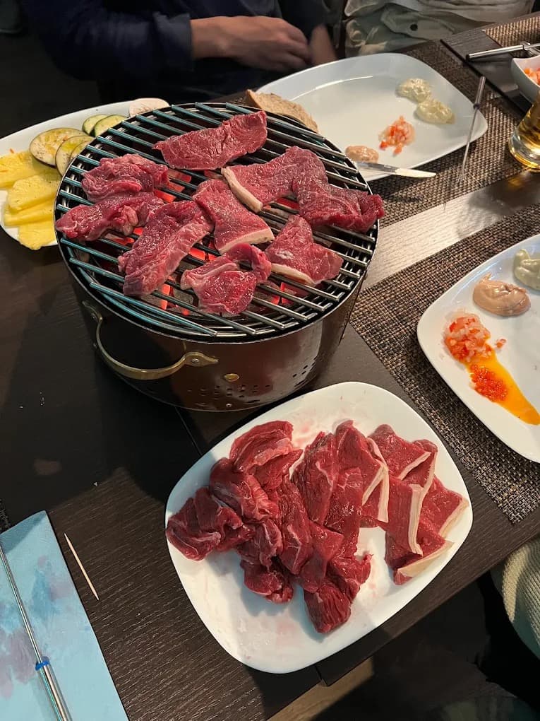 Charbonnade au Restaurant Acacia : viandes à griller sur un grill à charbon posé sur la table